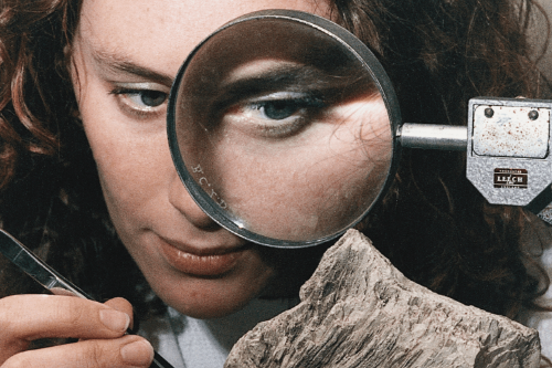 Person examining rock with magnifying glass