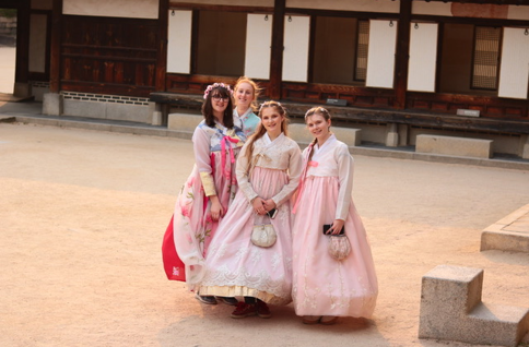 A group of women in dresses posing for a photo
Description automatically generated