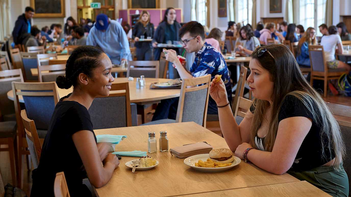 Students chatting over lunch in founders dining hall - Our campus eating and drinking