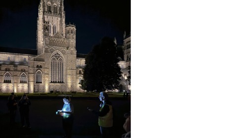 English academic Briony Hughes doing a night time reading in front of illuminated church