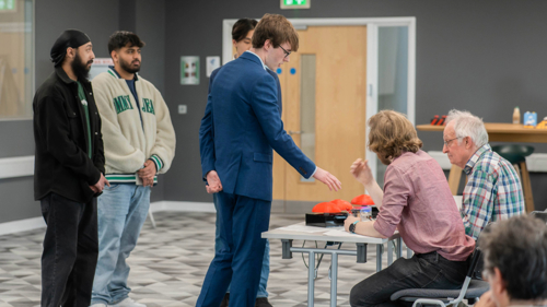 Four male students talking about their design prototype in front of industry panel
